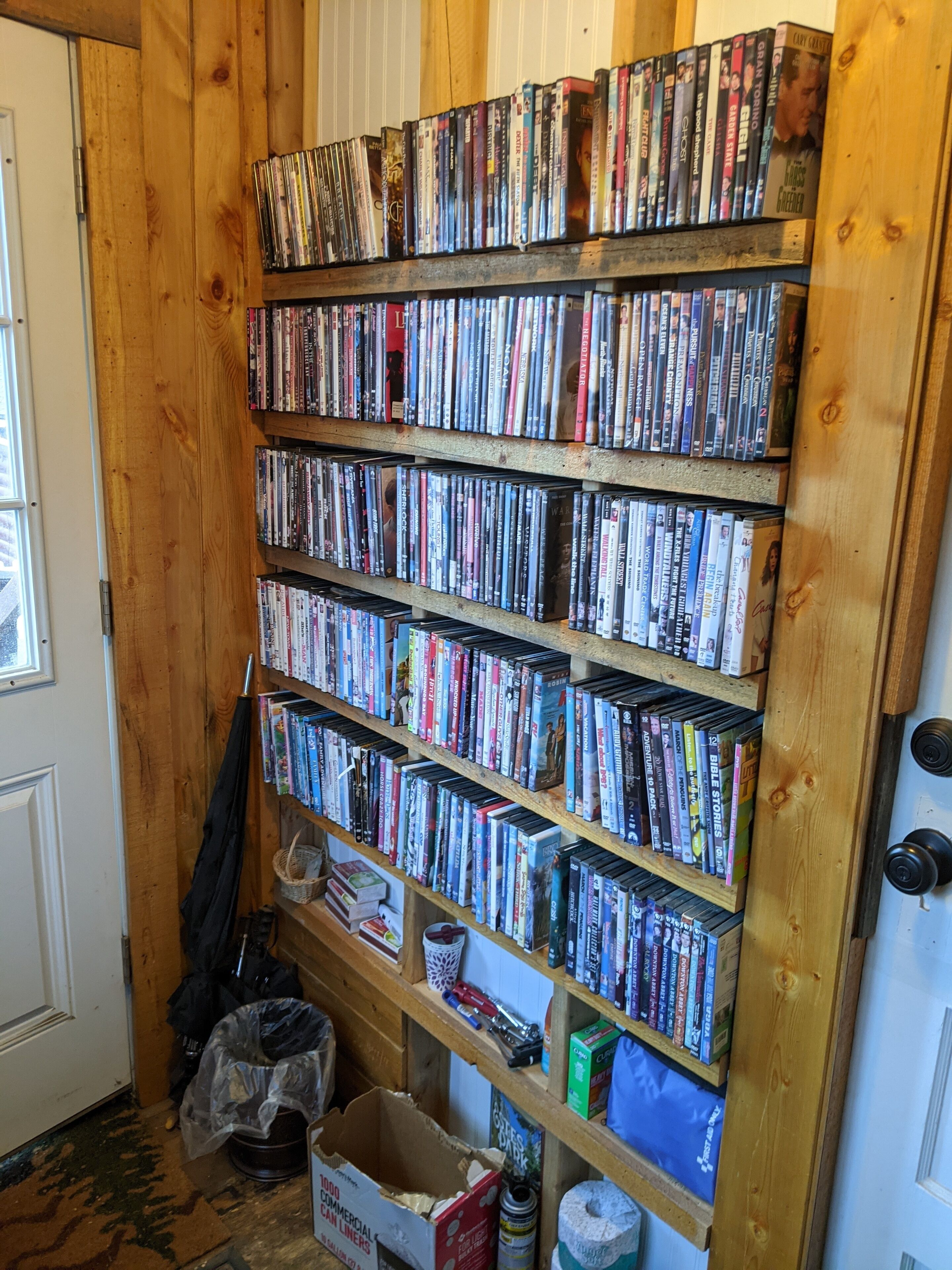 A wooden bookshelf filled with various books and DVDs.
