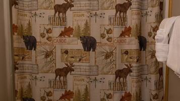 A bathroom with a shower curtain featuring a nature-themed print, a toilet, and a sink.