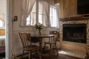Zona pranzo con tavolo rotondo, quattro sedie di legno e un vaso con fiori.