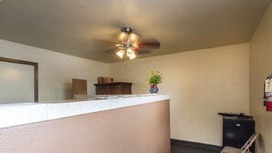 A kitchen with a white countertop, a ceiling fan, a potted plant, and a black trash bin. - Relax Inn (Manor)