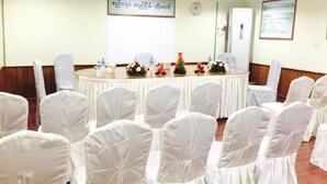 A conference room with a round table, white chairs, and floral centerpieces. - Summer Palace Hotel (Yangon)