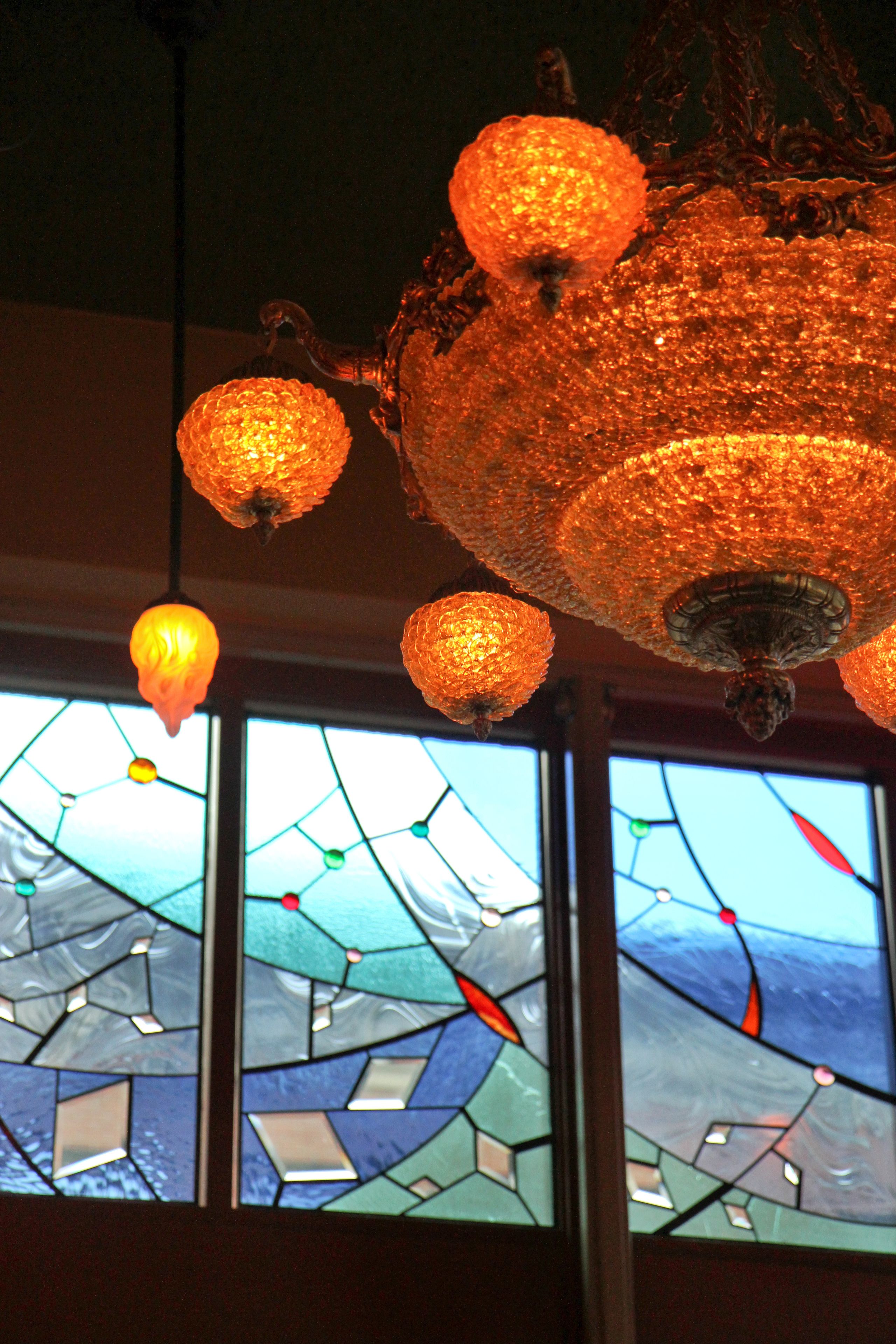 A chandelier with spherical glass bulbs and a stained glass window with geometric patterns.