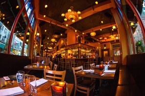 A restaurant interior with wooden tables, chairs, and a bar area. - McMenamins Crystal Hotel (Portland)