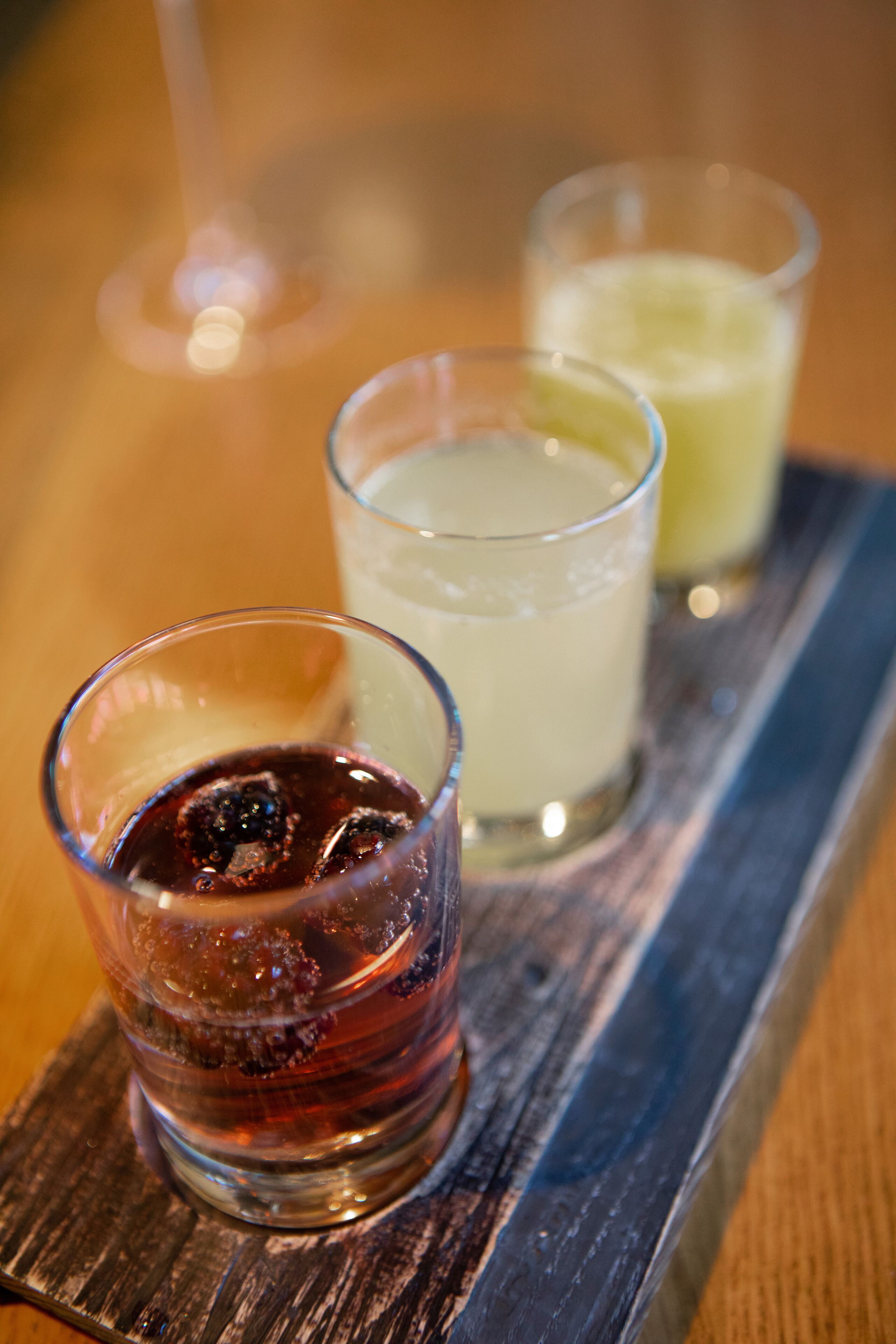 Trois verres de boissons sur un plateau en bois.