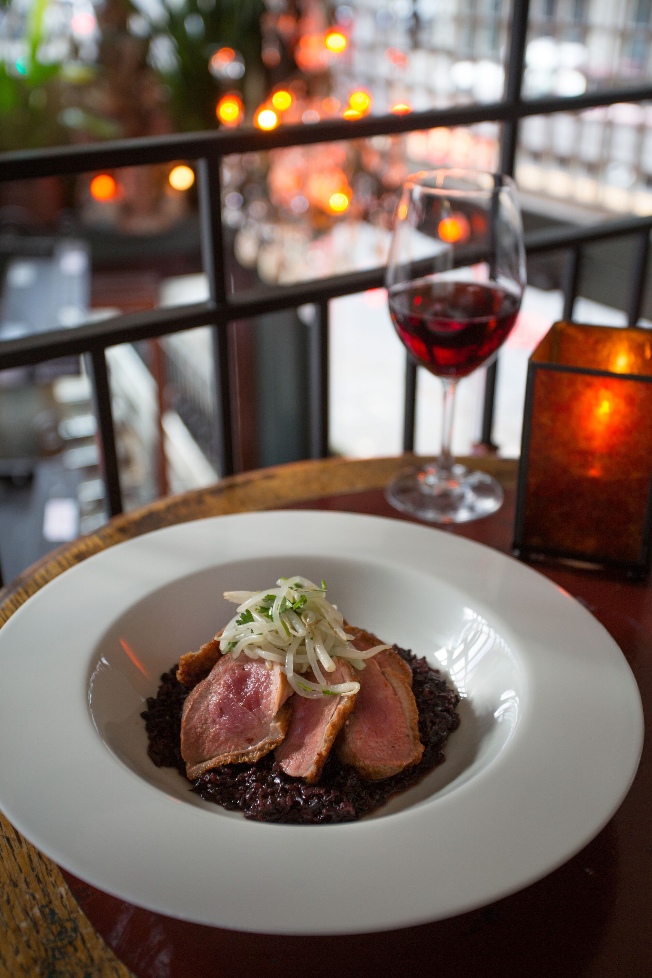 Une assiette de nourriture, un verre de vin rouge et une bougie sur une table.