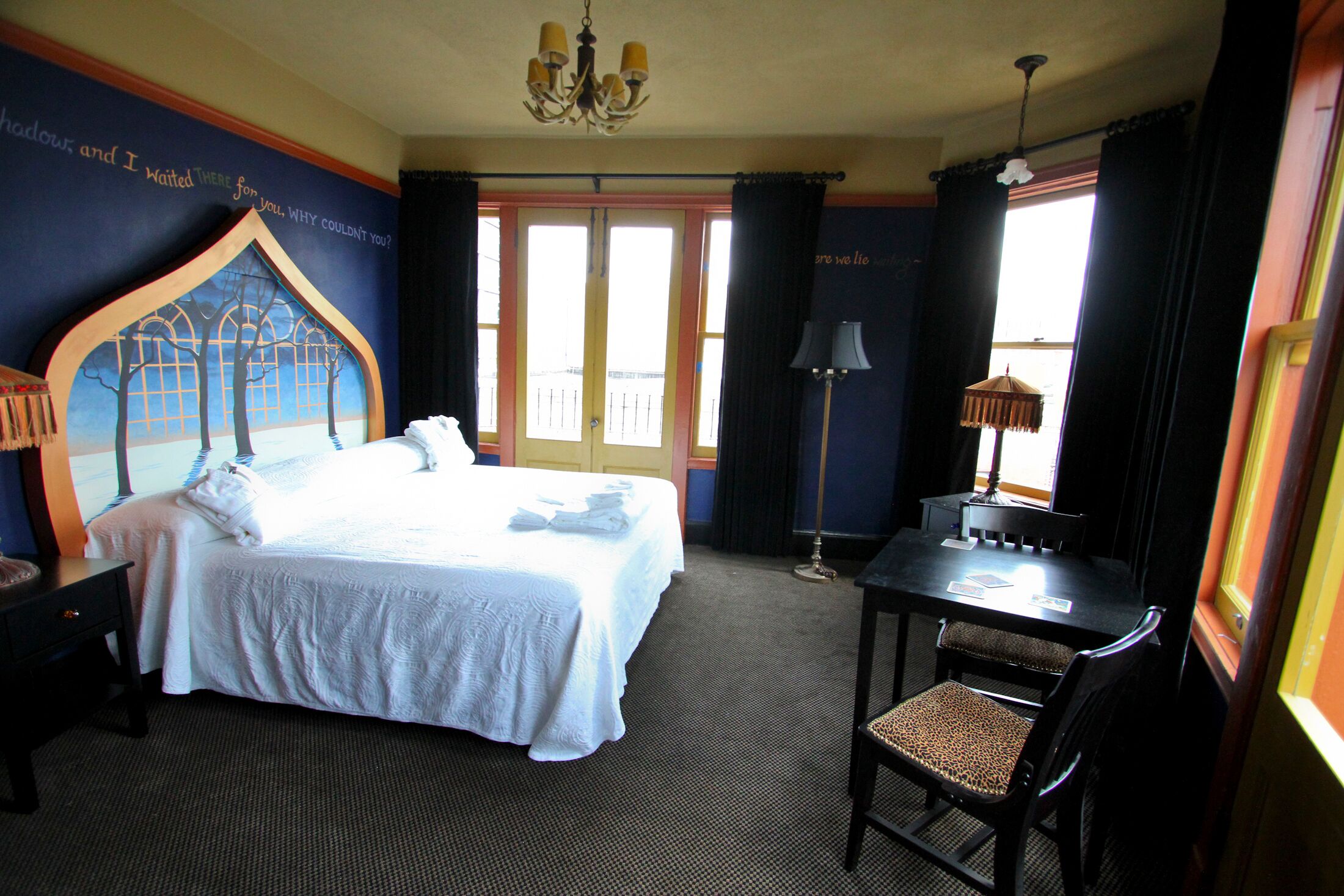 Ein Hotelzimmer mit einem großen Bett, einem Schreibtisch mit Stuhl, einer Deckenleuchte und Blick nach außen.