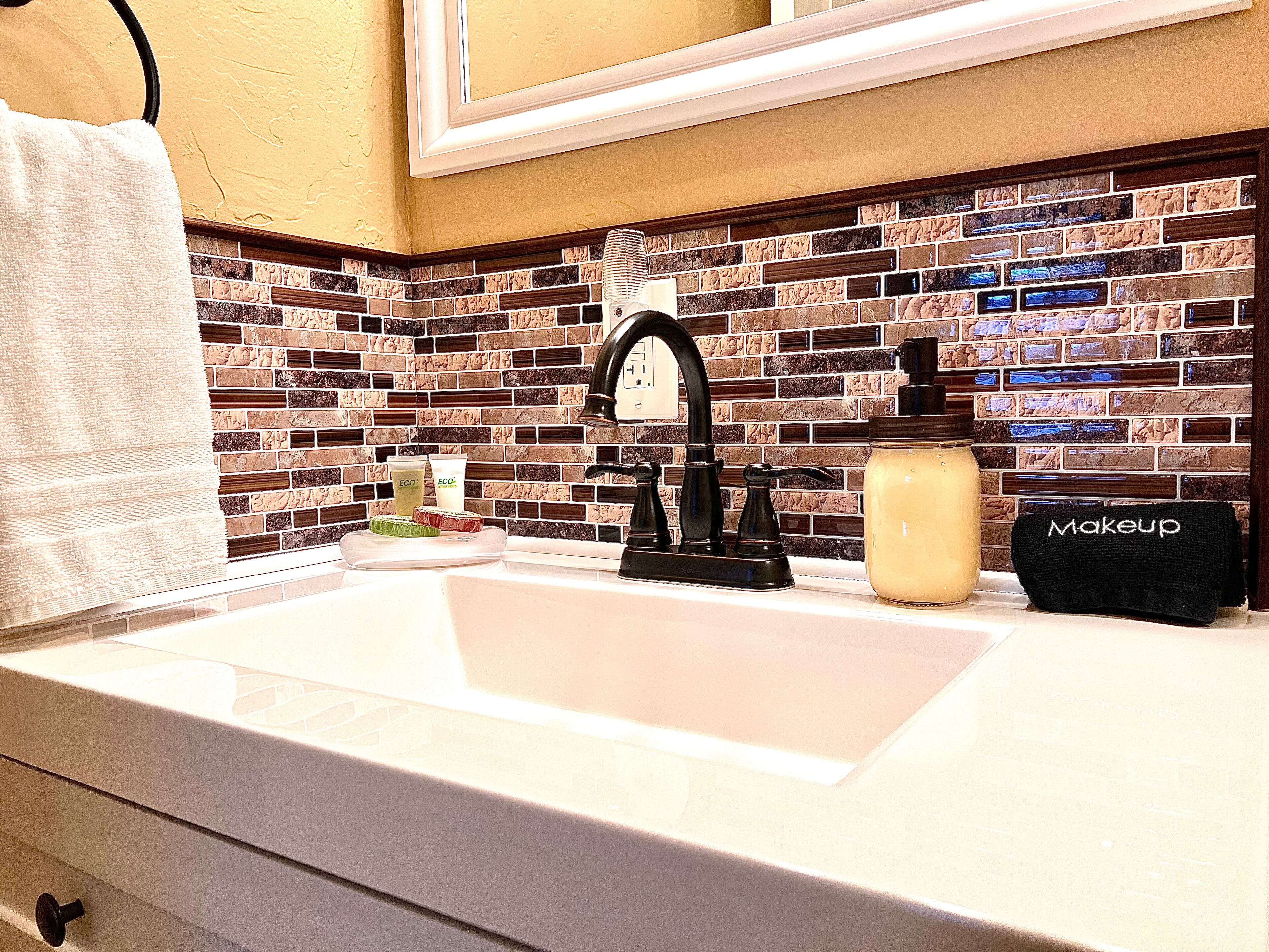 A bathroom with a white sink, black faucet, and a tiled backsplash.