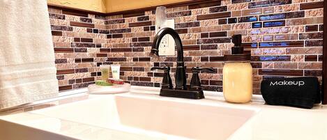 A bathroom with a white sink, black faucet, and a tiled backsplash.