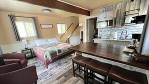 A compact hotel room with a bed, a desk, a kitchenette, and a staircase. - Chinook Wind Cabins (Talkeetna)