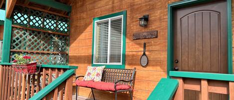 A wooden deck with a bench and a door.