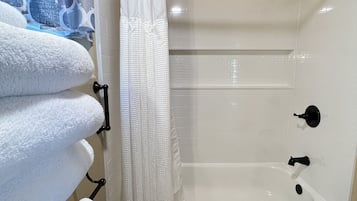 Un baño con bañera, cortina de ducha y varias toallas.