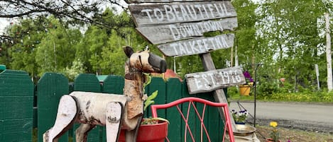 A wooden dog sculpture with a sign that reads "WELCOME TO BEAUTIFUL DOWNTOWN TALKEETNA EST. 1915."