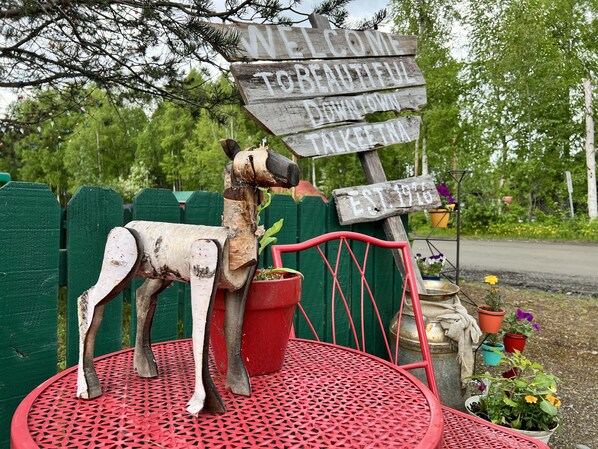 Una escultura de madera de un perro con un letrero que dice "BIENVENIDOS A DOWNTOWN TALKEETNA FUNDADA EN 1915".