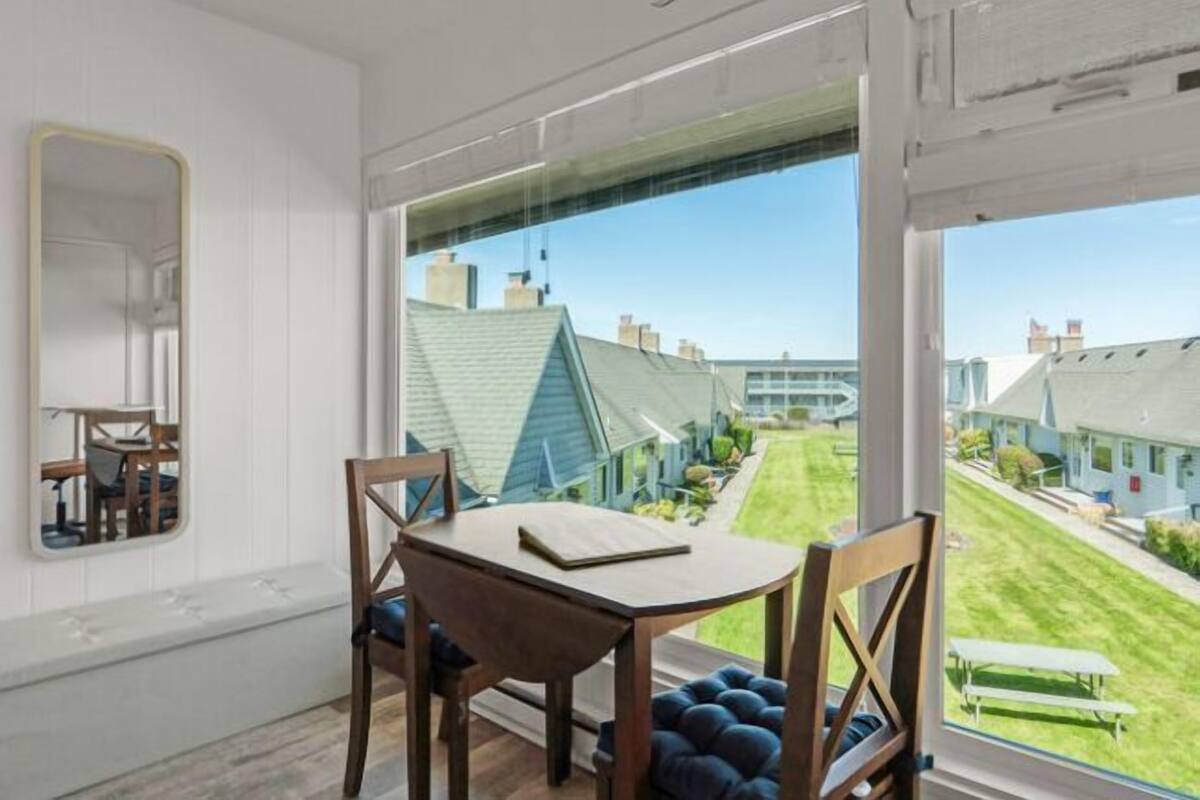 A room with a large window, a wooden table, and a chair.