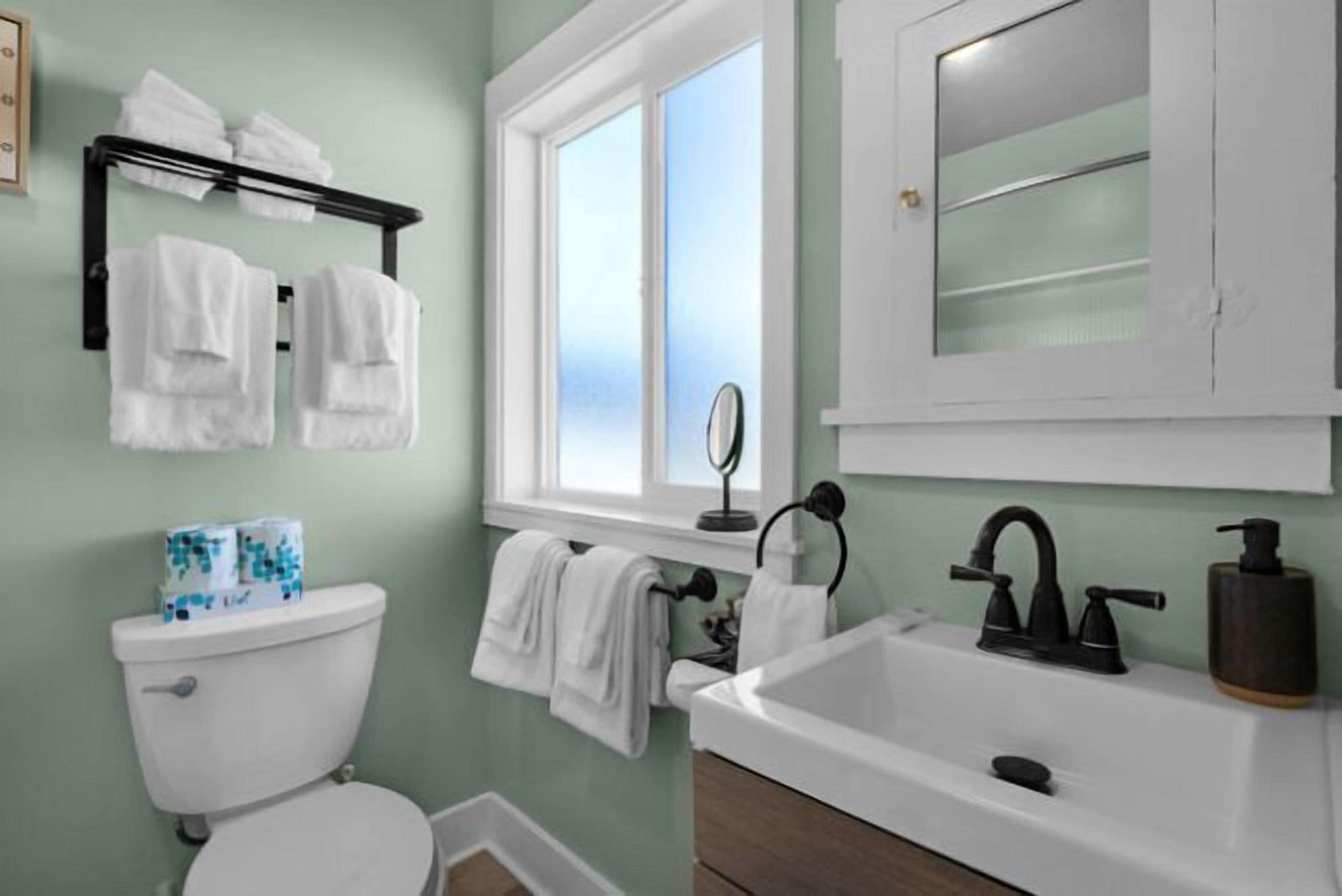 A bathroom with a toilet, sink, and window.