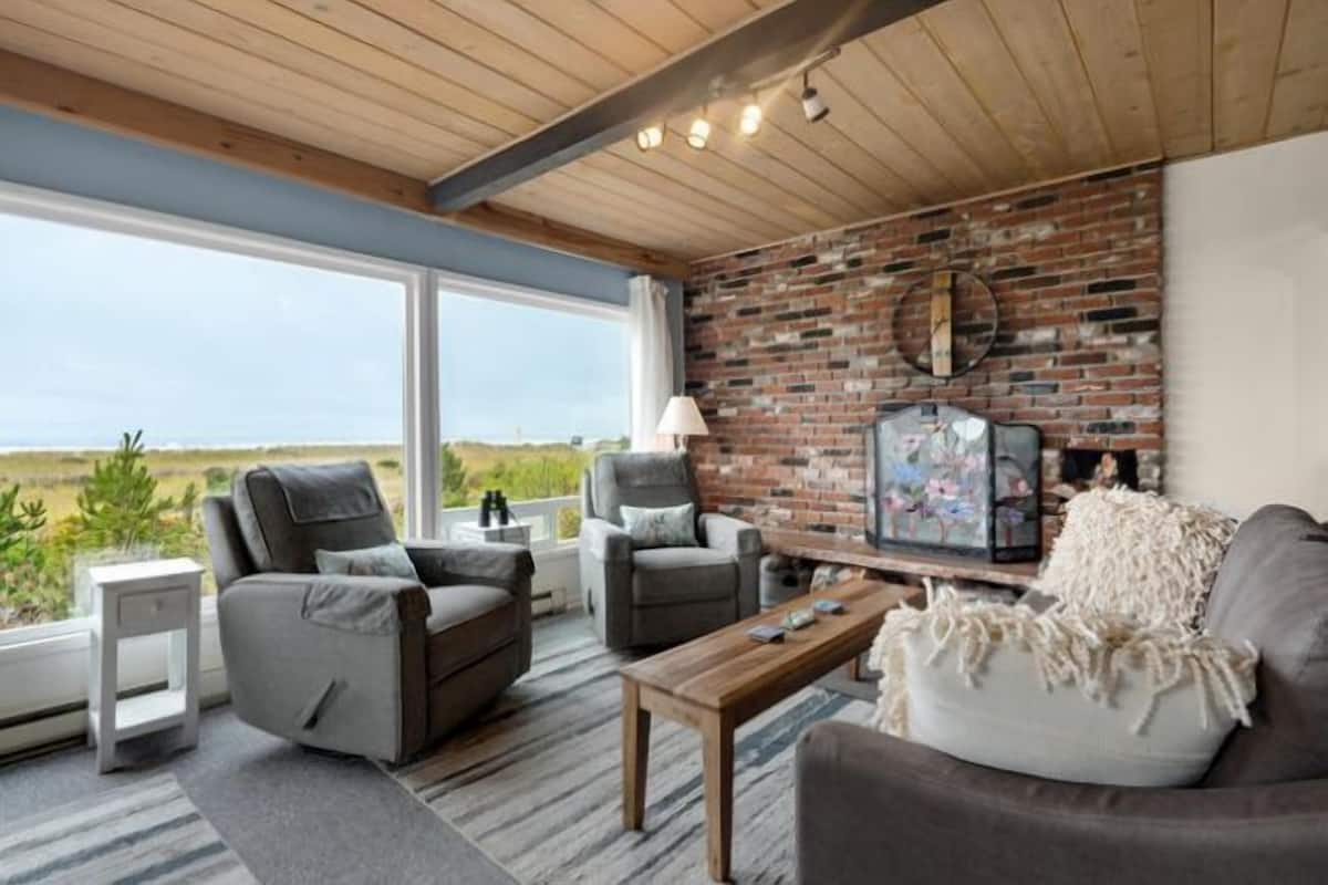 A modern living room with a large window, a brick wall, and a view of the outdoors.
