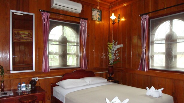 A wooden room with a bed, a desk, and a window with curtains. - Villa Philaylack (Luang Prabang)