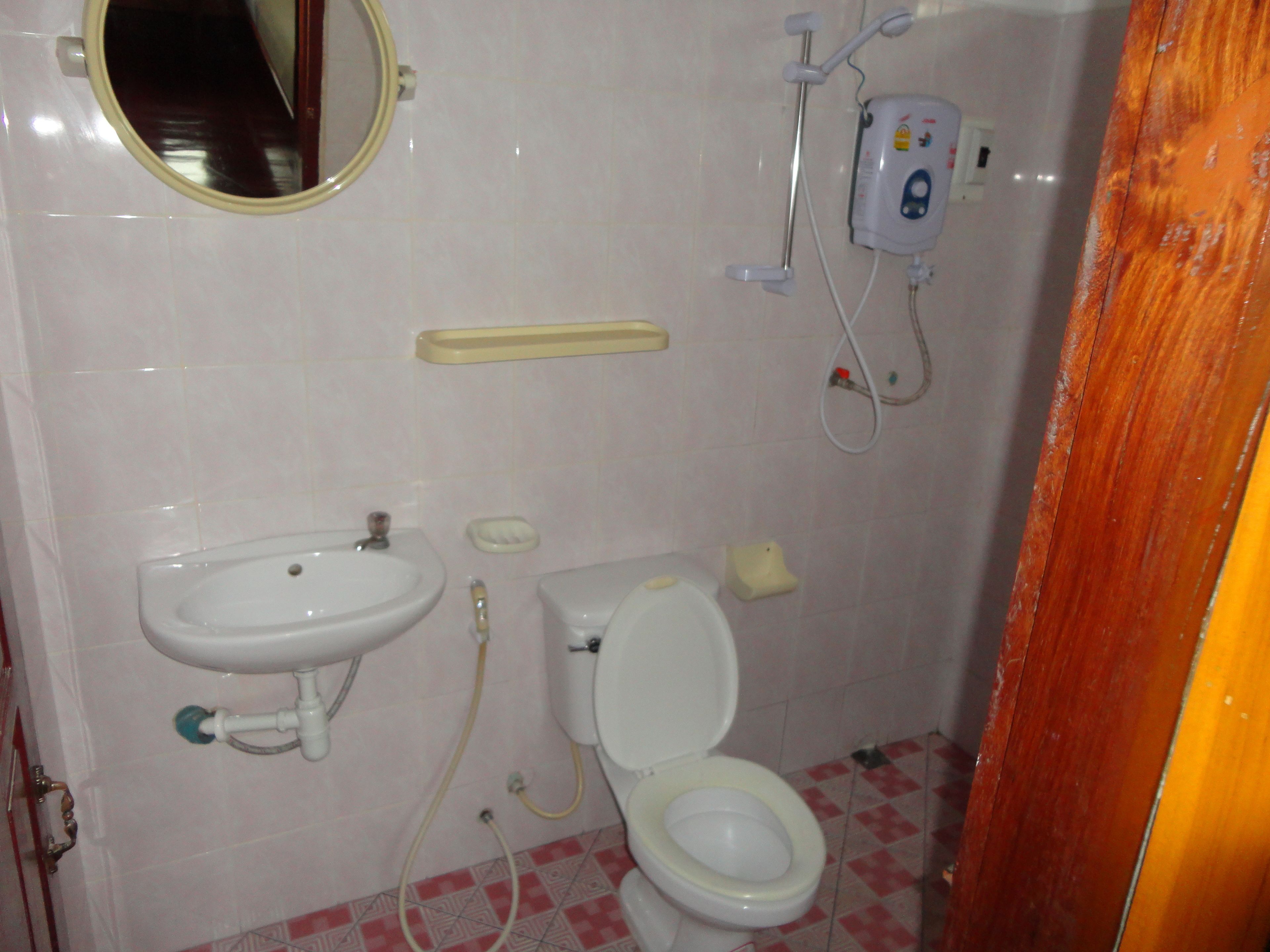 Un baño con lavamanos, inodoro y espejo.