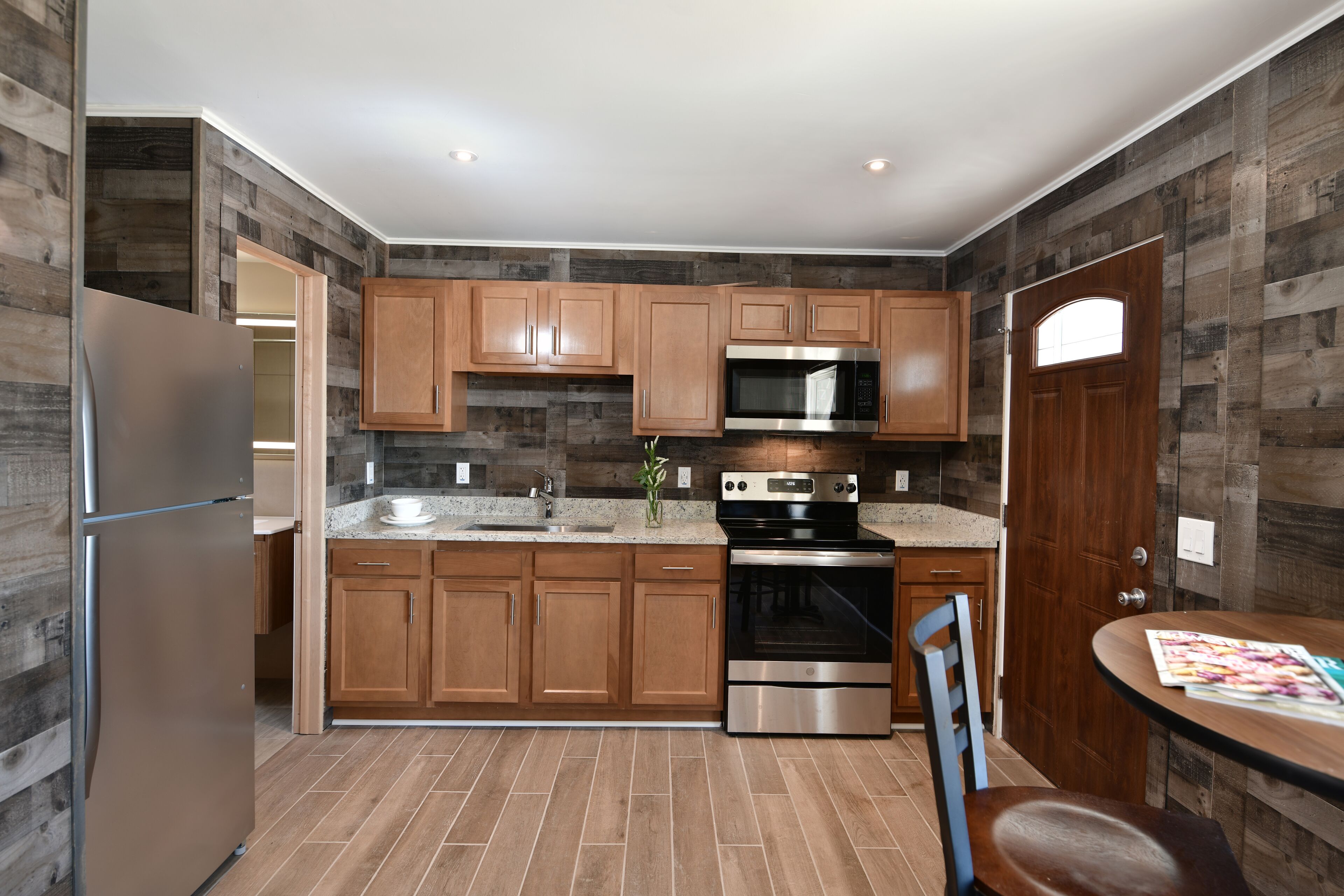 A modern kitchen with wooden cabinets, stainless steel appliances, and a tiled floor.