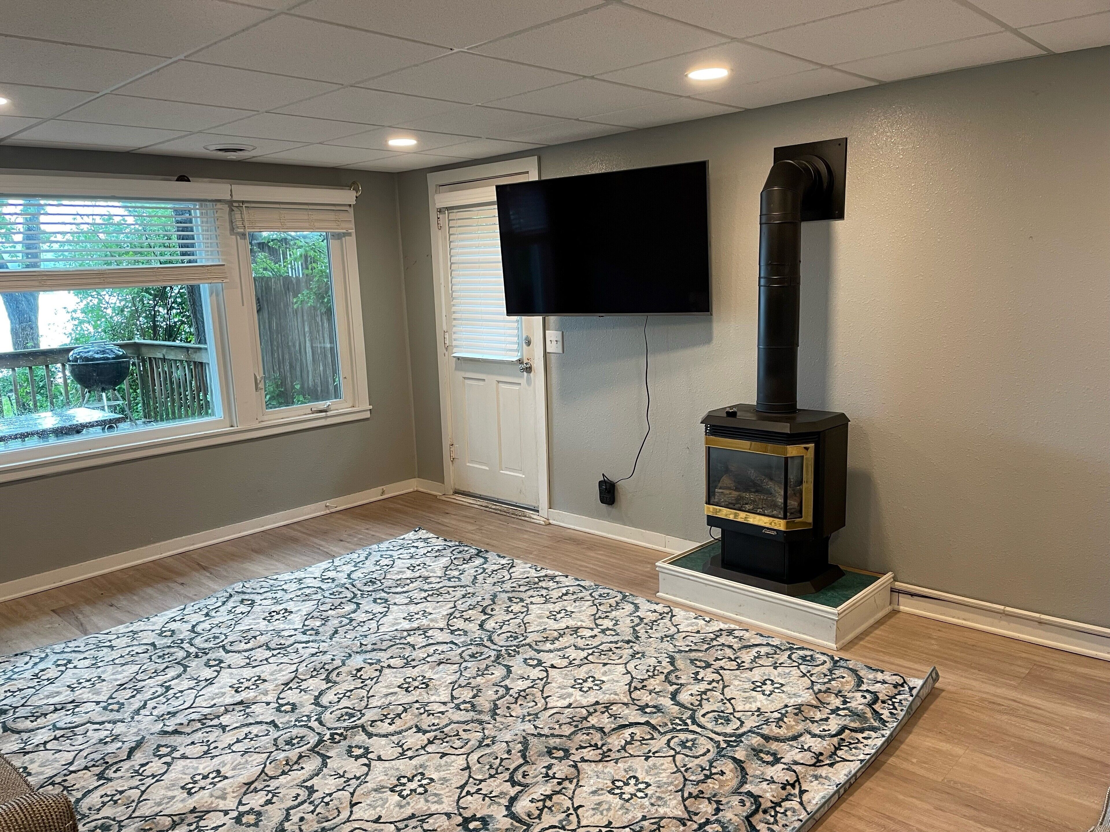A room with a fireplace, a television mounted on the wall, and a patterned rug on the floor.