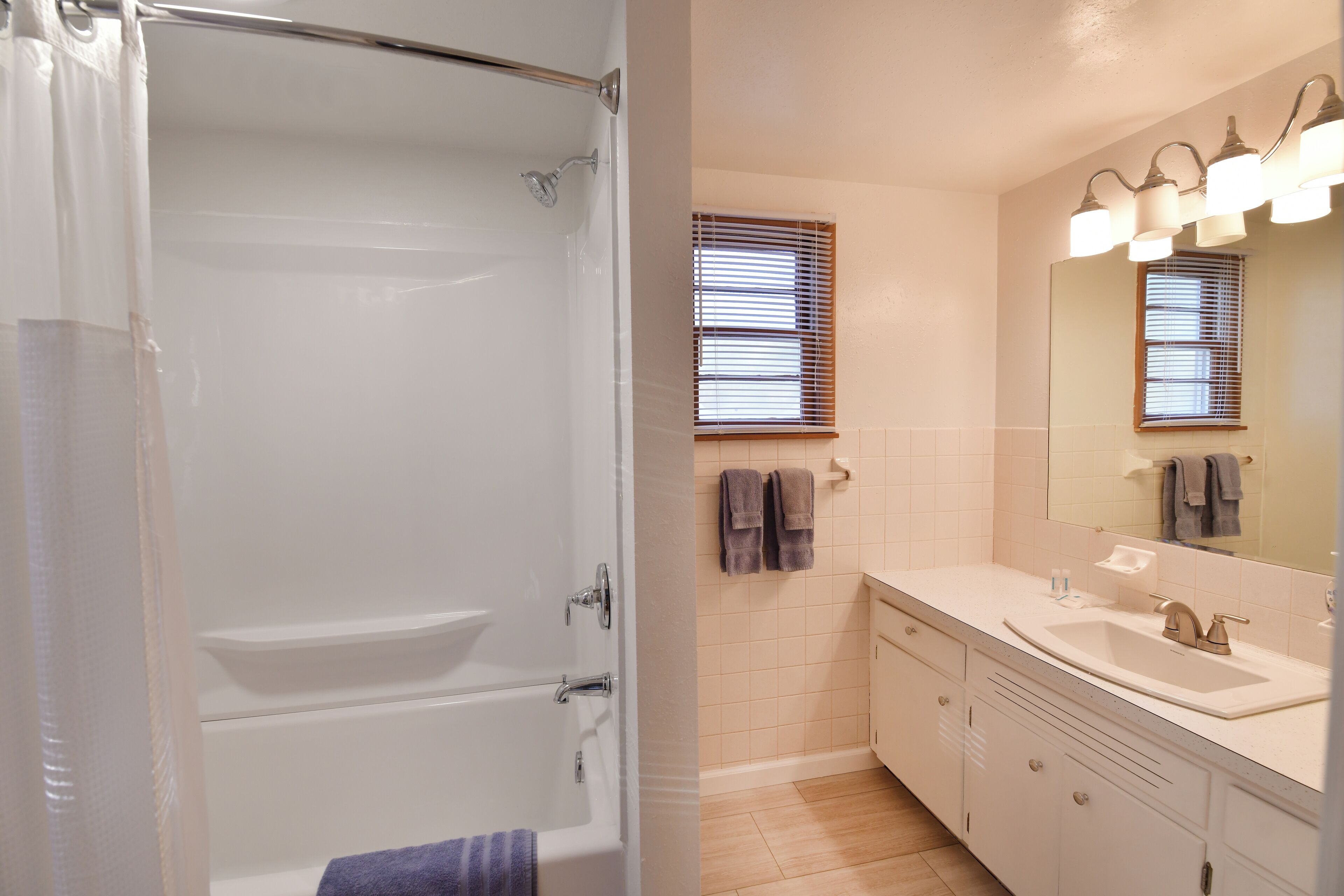 Une salle de bain avec une baignoire, un lavabo et un miroir avec éclairage intégré.