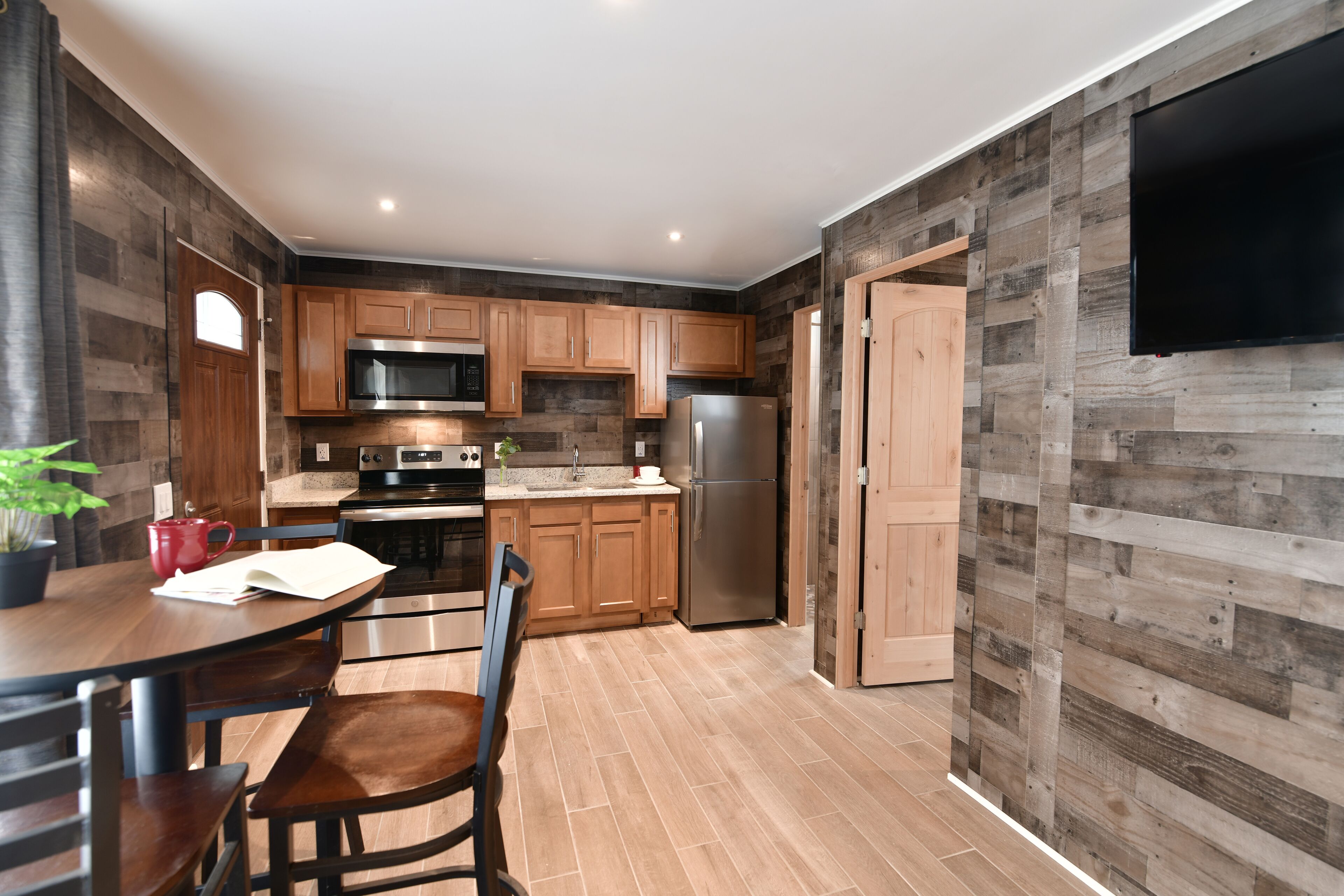 A modern kitchen with wooden cabinets, stainless steel appliances, and a dining area with a table and chairs.