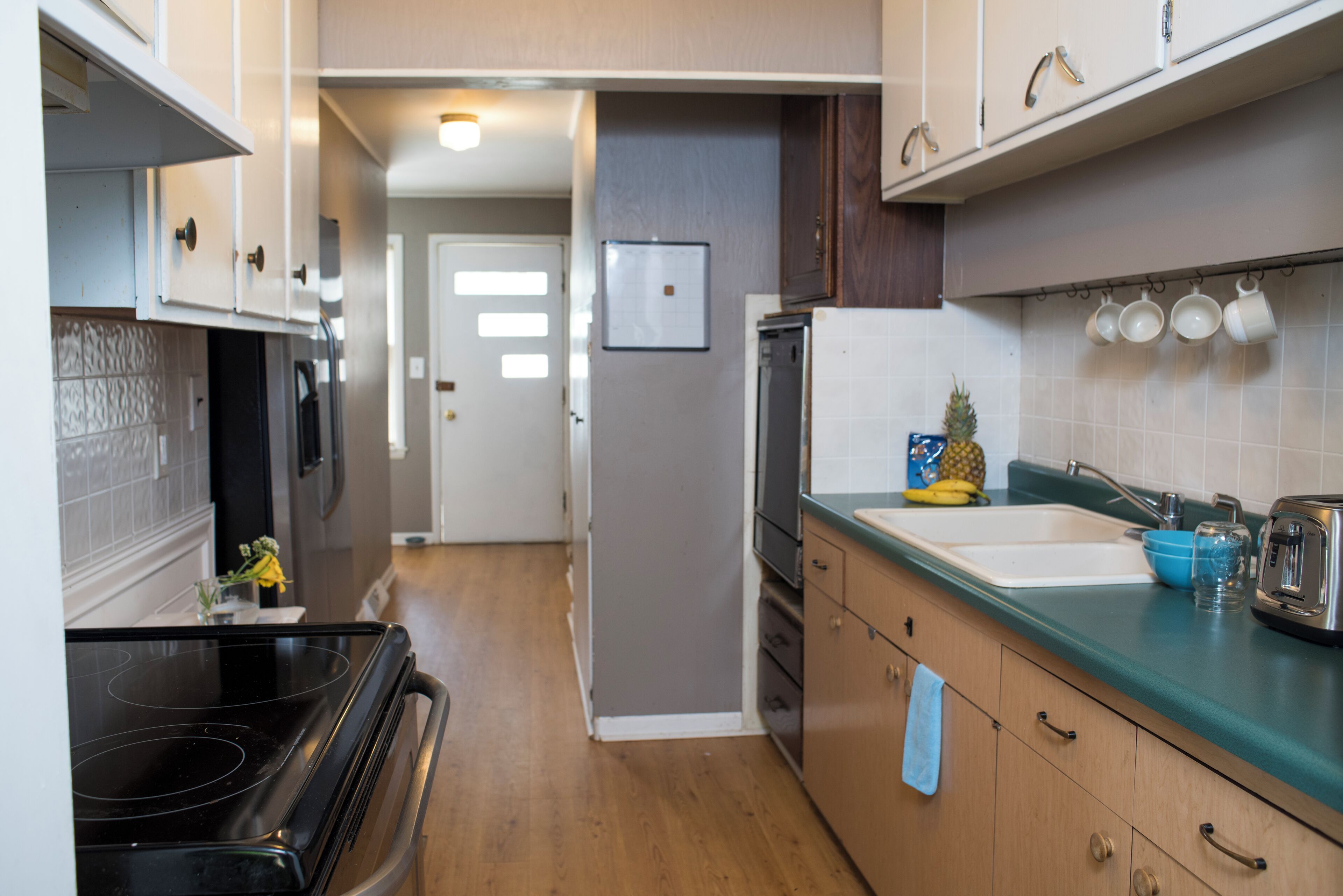 A kitchen with a stove, sink, and cabinets.