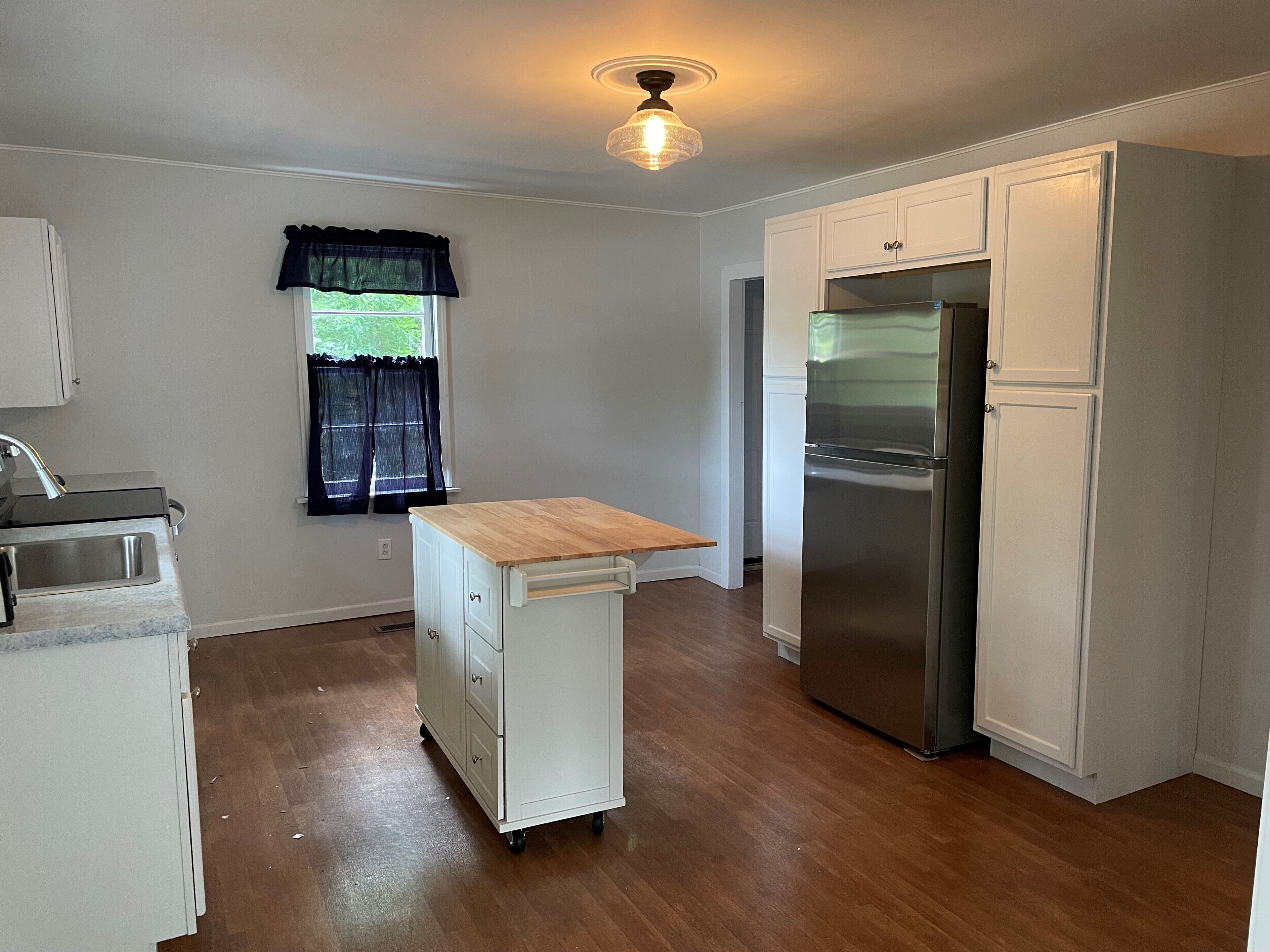 A compact kitchen with a built-in refrigerator, a sink, and a wooden countertop.