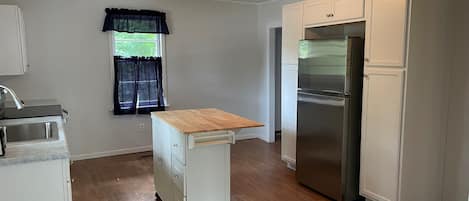 A compact kitchen with a built-in refrigerator, a sink, and a wooden countertop.