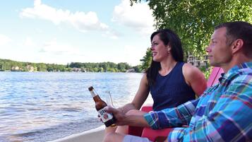 Two people sitting by a lake, one holding a beer bottle.