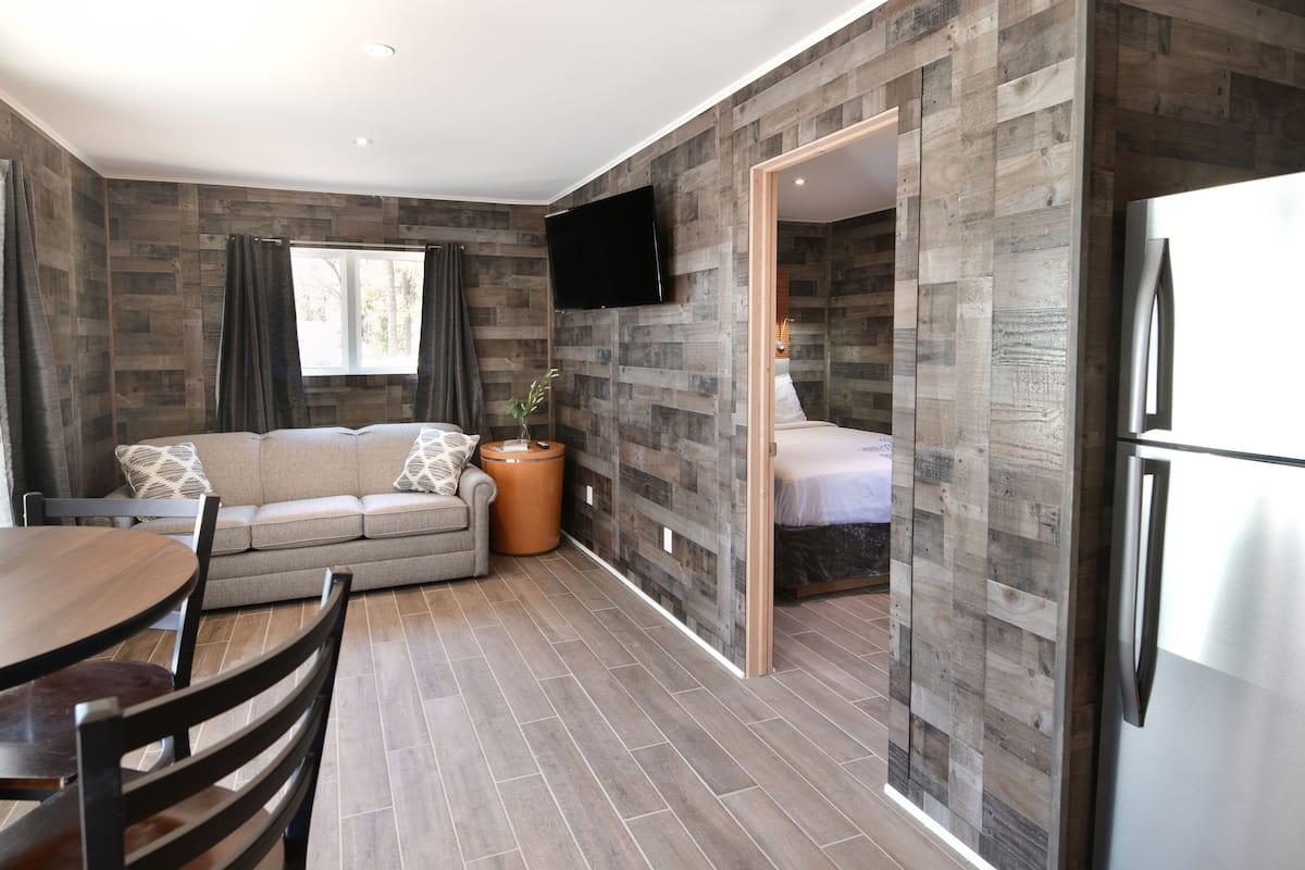 A modern room with a sofa, dining table, chairs, a flat-screen TV, and a refrigerator.