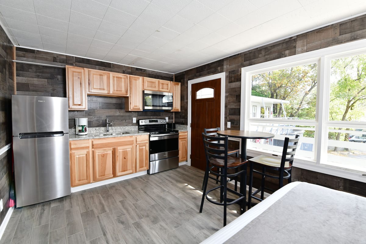 A modern kitchen with wooden cabinets, stainless steel appliances, and a dining area with a table and chairs.