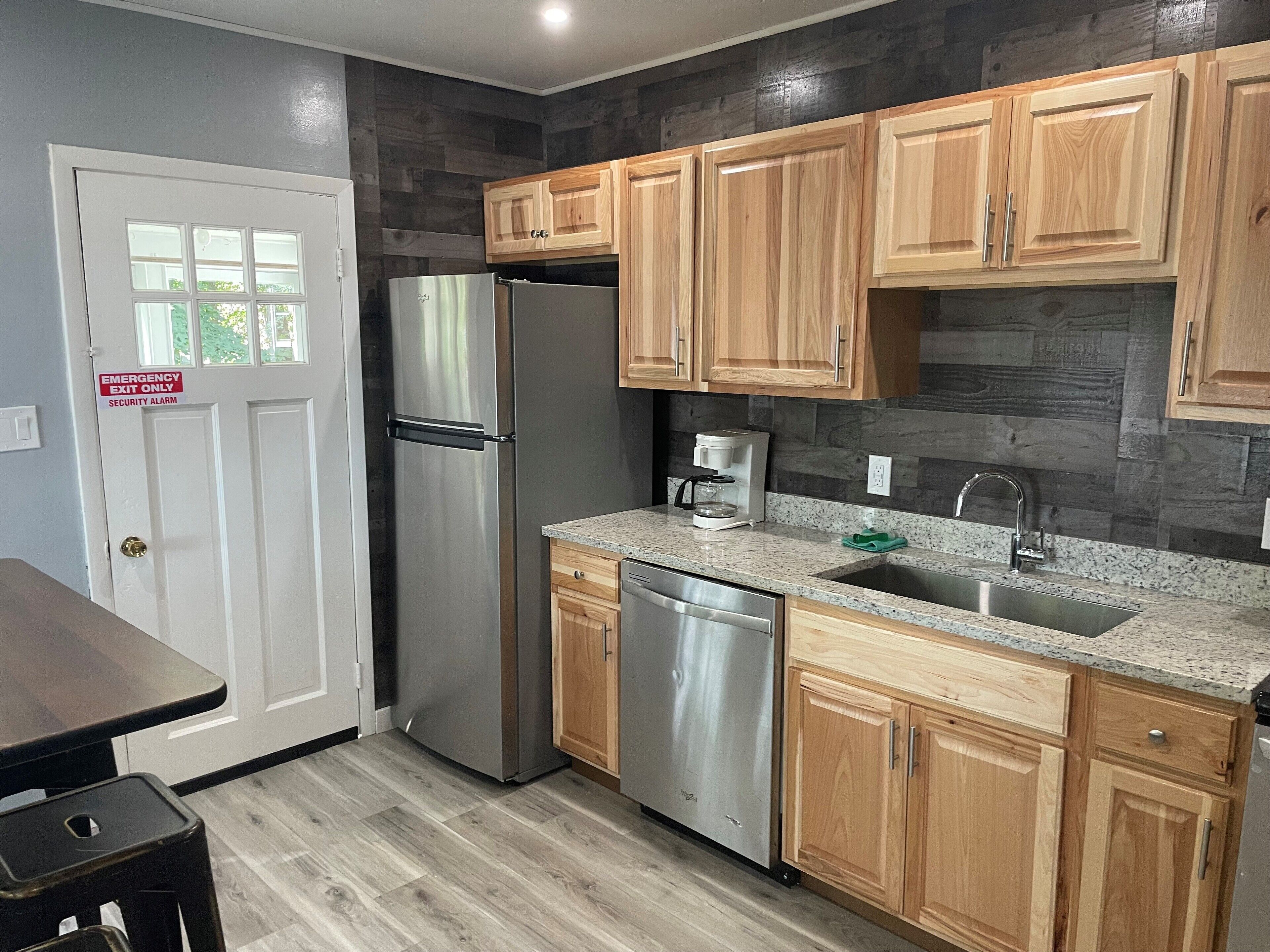 A modern kitchen with wooden cabinets, stainless steel appliances, and granite countertops.