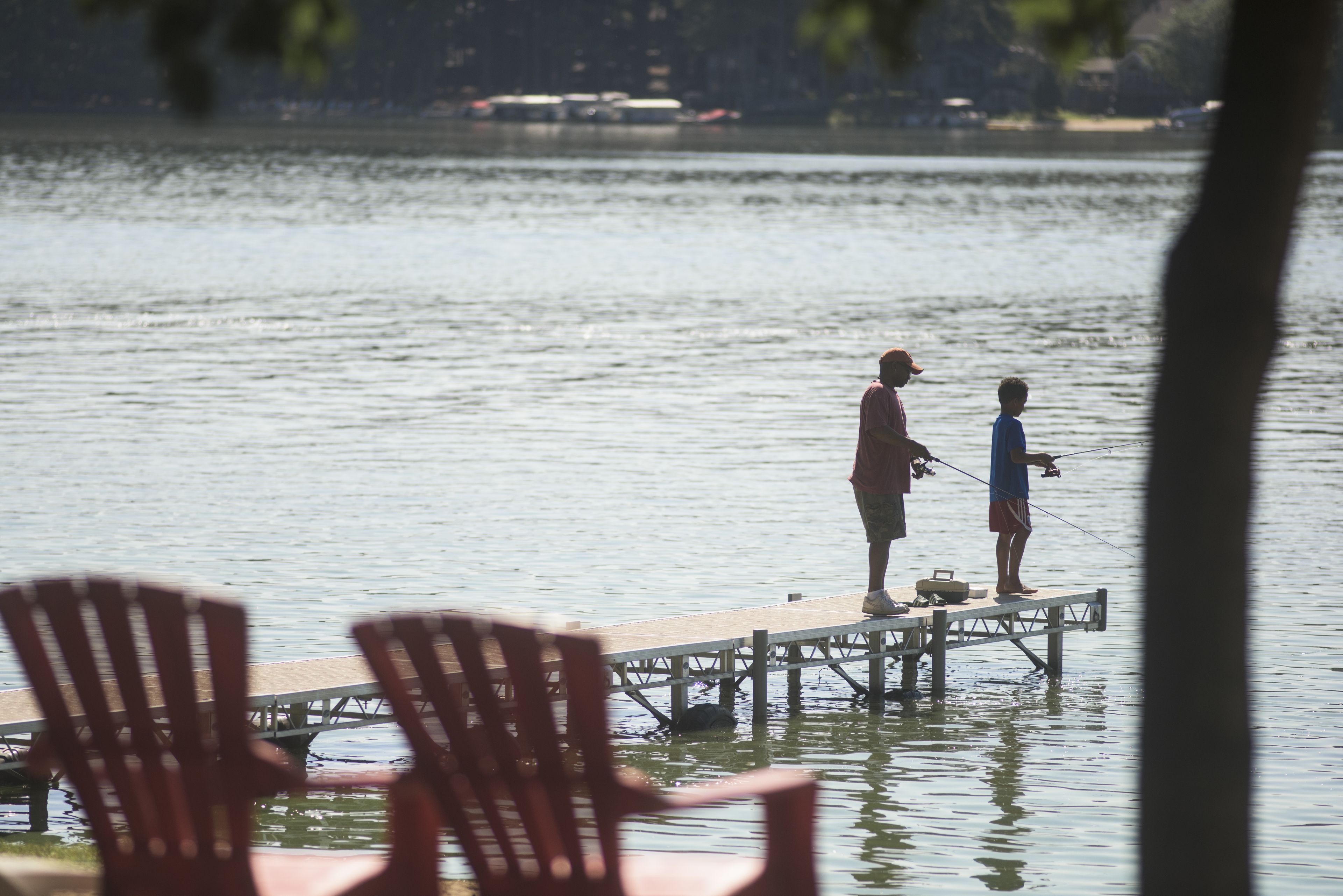 Une jetée s’avançant dans une étendue d’eau calme, où deux personnes pêchent.