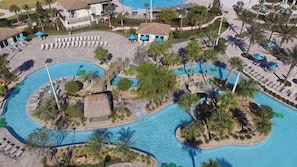 An aerial view of a resort with multiple swimming pools, lounge areas, and palm trees.