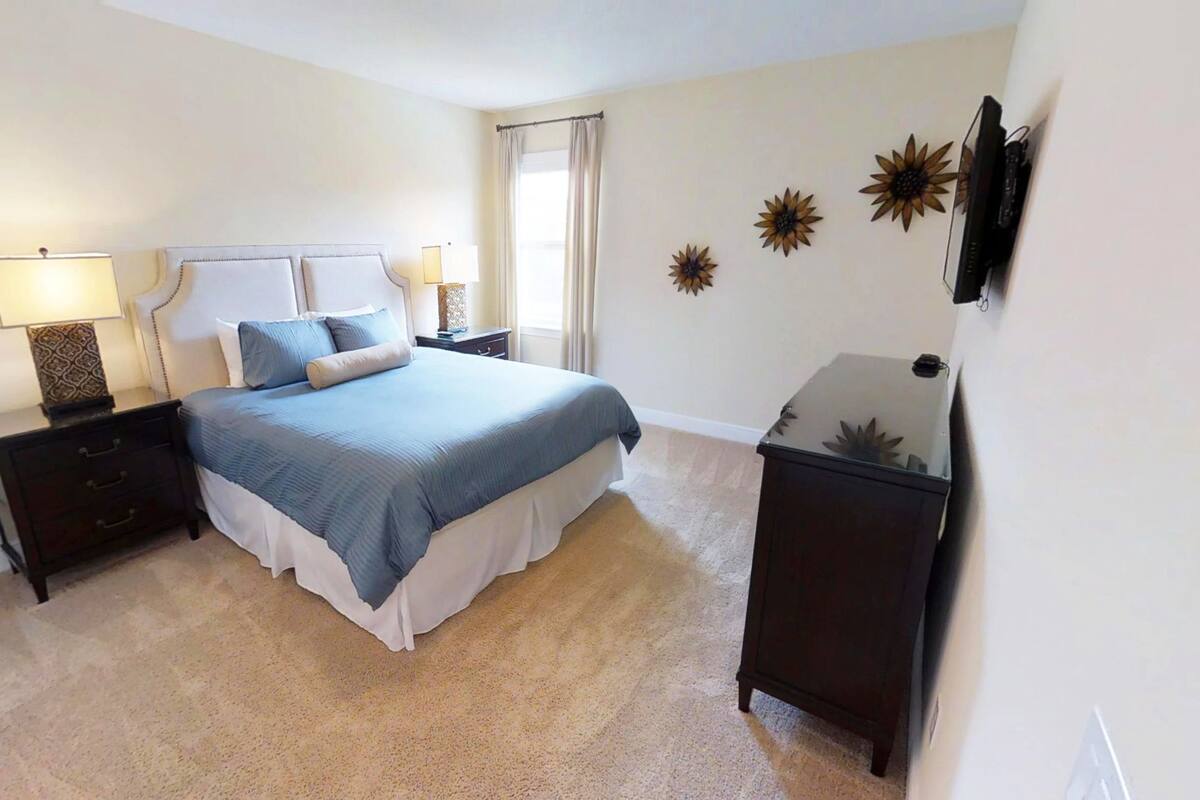 Une chambre à coucher comprenant un lit, deux tables de chevet, une commode et des éléments de décoration murale.