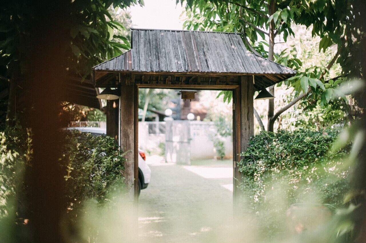 A wooden archway leading to a pathway in a garden setting.