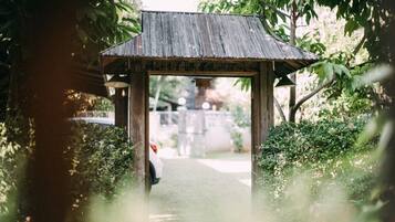 A wooden archway leading to a pathway in a garden setting.