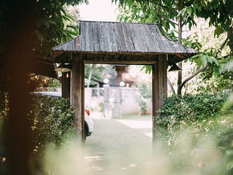 A wooden archway leading to a pathway in a garden setting.