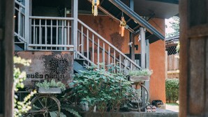 A rustic building with a staircase, a bicycle, and hanging lanterns. - Hueandin Klinmai Boutique Hotel (Chiang Mai)
