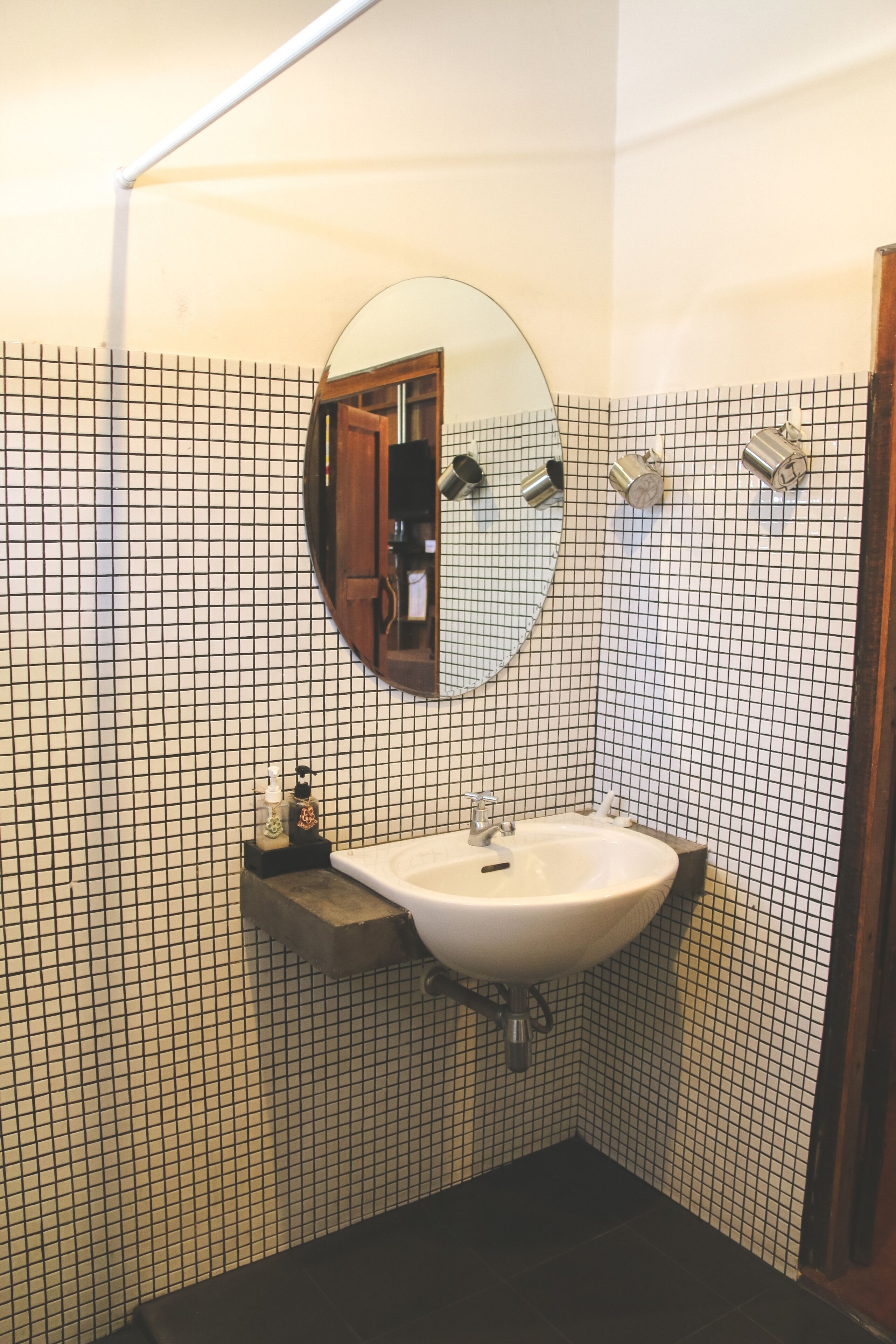 A bathroom with a white sink, a mirror, and a tiled wall.