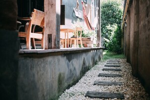 A pathway with wooden steps leading to a seating area with wooden chairs and a hammock.