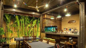 A restaurant with a bamboo backdrop, wooden furniture, and a fish tank. - Hueandin Klinmai Boutique Hotel (Chiang Mai)