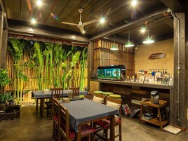 A restaurant with a bamboo backdrop, wooden furniture, and a fish tank.