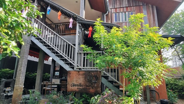 A traditional building with a wooden exterior, a staircase leading to a balcony, and a sign in a local language. - Hueandin Klinmai Boutique Hotel (Chiang Mai)