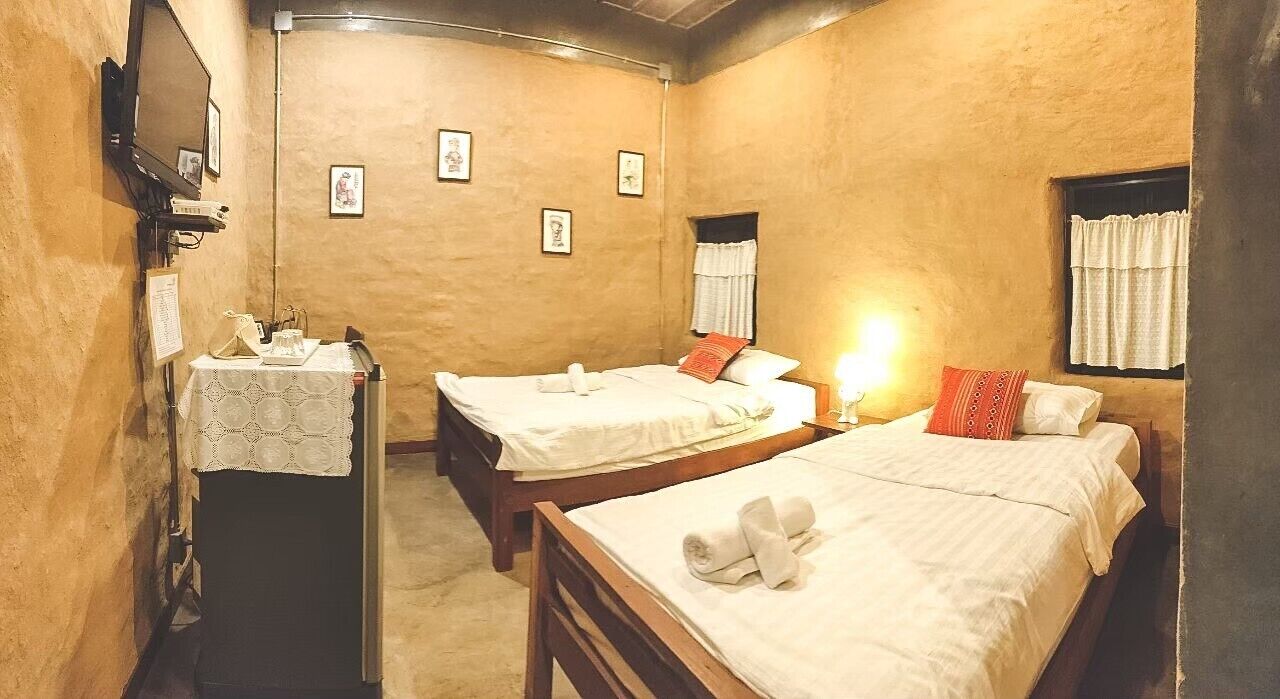 Ein Zimmer mit zwei Betten, einem Schreibtisch mit Lampe und gerahmten Bildern an der Wand.