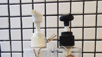 Two glass bottles with pump dispensers, each labeled with a different brand of shampoo, placed on a black crate.