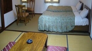 A room with a bed, a wooden table, a chair, and a small table with a bowl. - Charade Inn Shiga (Yamanouchi)