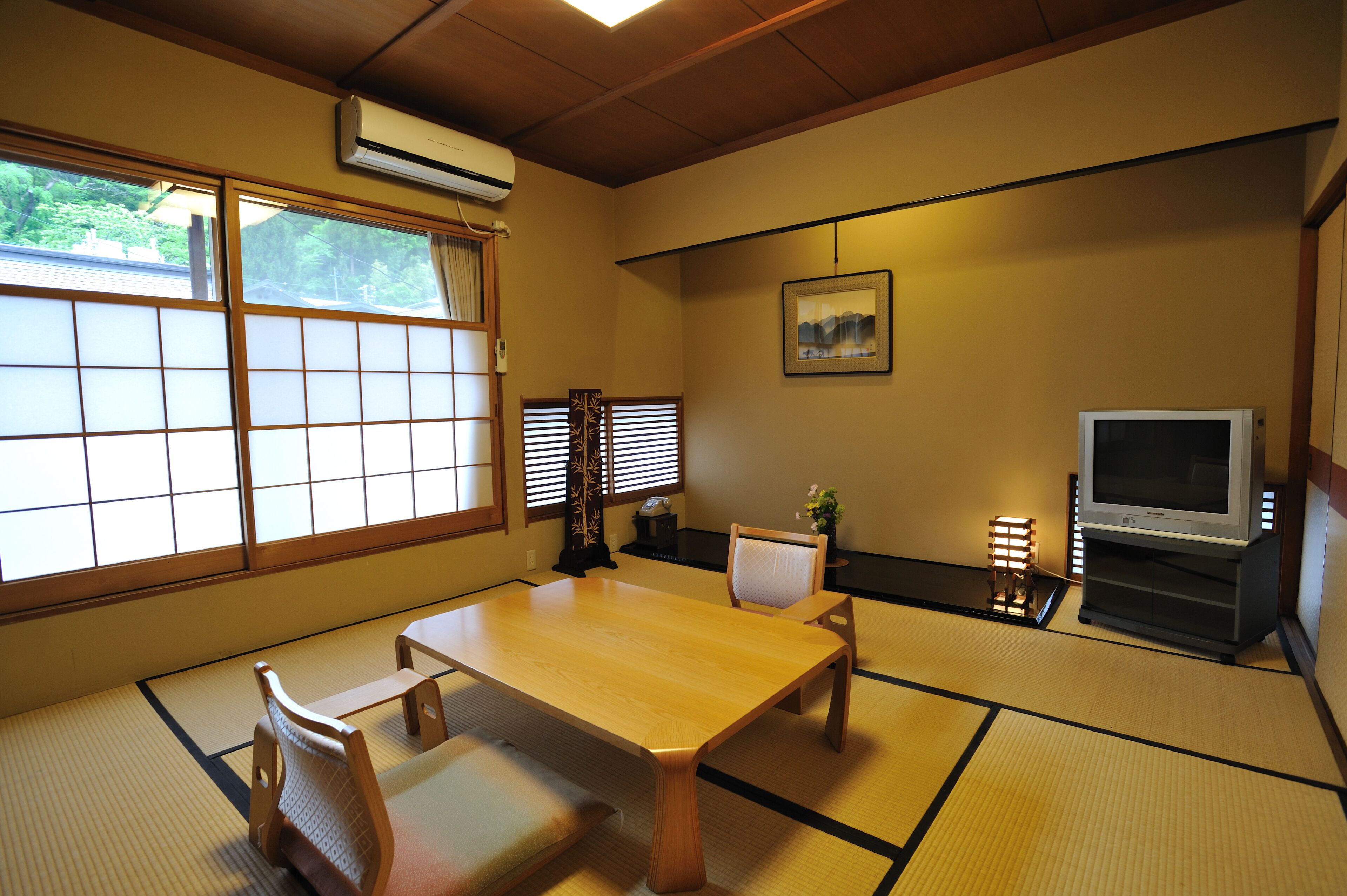 A traditional Japanese room with tatami flooring, a low table, and a television.