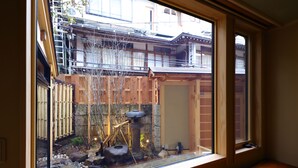 A traditional Japanese garden with a wooden fence, a stone lantern, and a small pond. - Shibu Onsen KOKUYA (Yamanouchi)